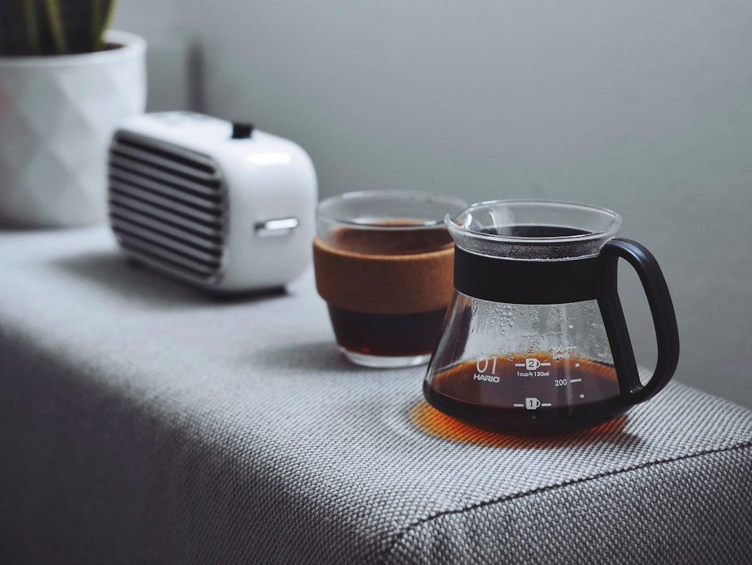 A pour-over coffee carafe and cup of coffee next to a compact coffee gadget