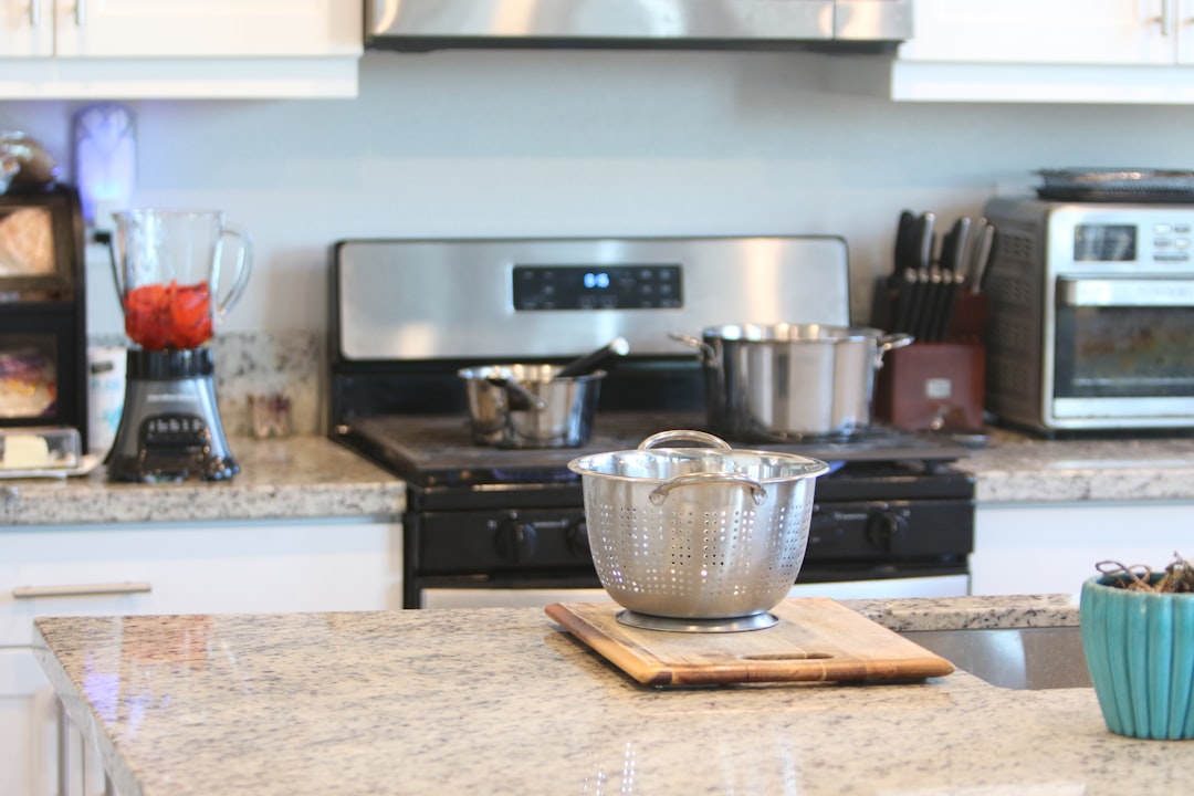 A stainless steel colander on a cutting board with mini kitchen appliances in the background