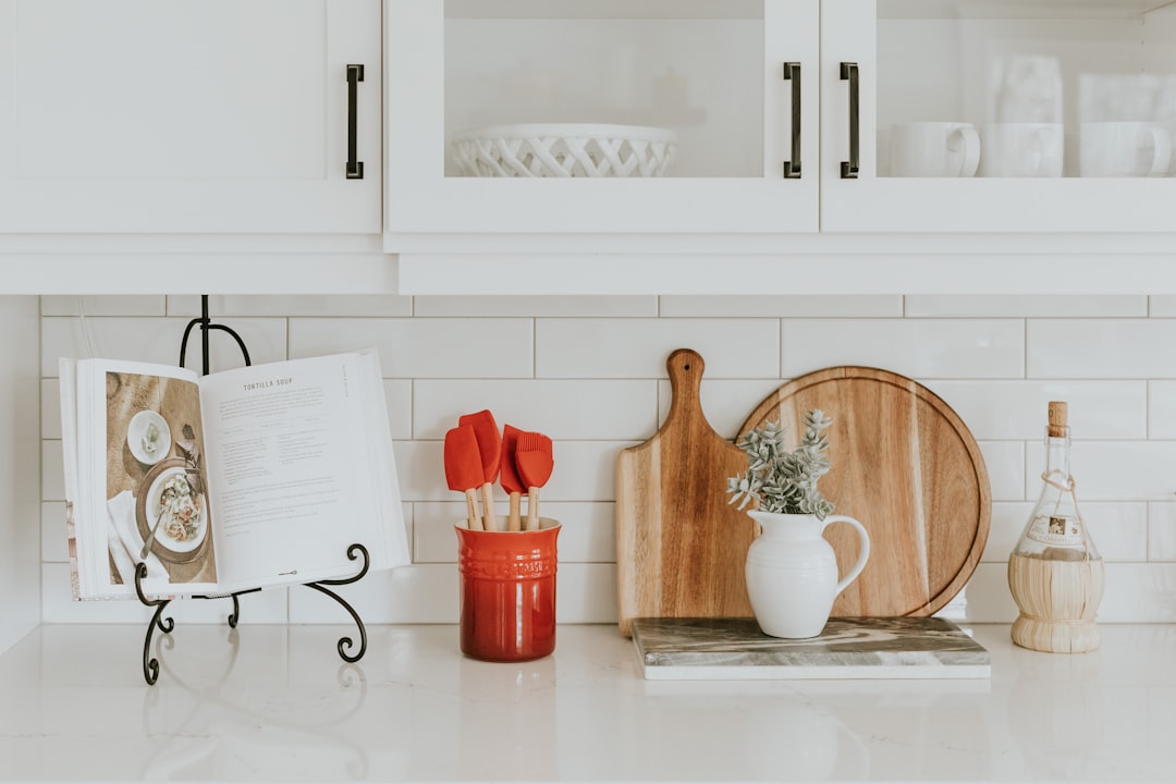 A tidy kitchen counter with a cookbook stand, wooden cutting boards, and a crock of utensils