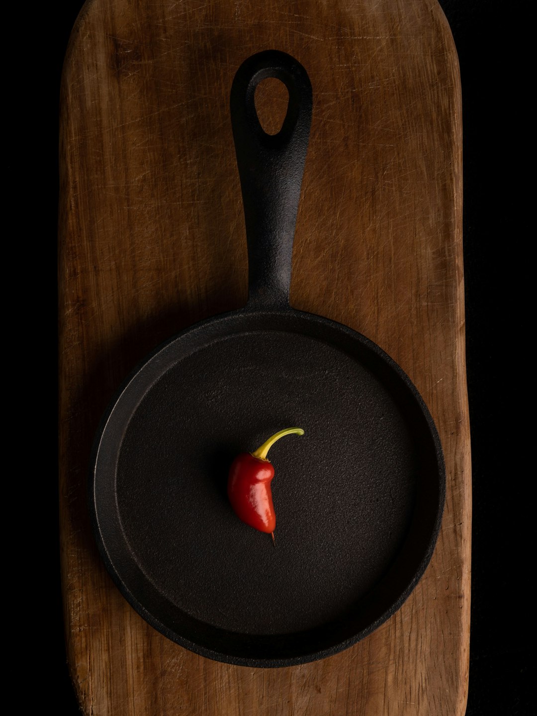 A red bell pepper resting in a well-seasoned cast iron skillet