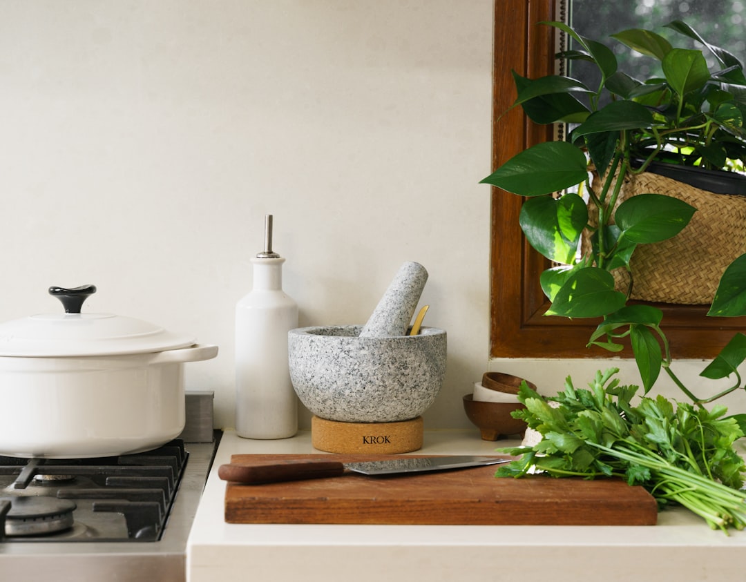 A kitchen counter with a Dutch oven, mortar and pestle, and a cutting board with a chef's knife