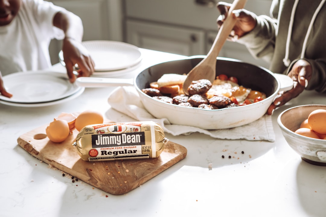 A family cooking breakfast together with a skillet of sausage and eggs on the counter